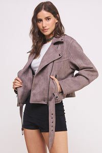 Woman wearing a gray suede jacket on a light pink background