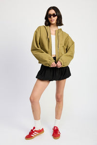 Person wearing a green hoodie, black skirt, white socks, and red sneakers on a white background