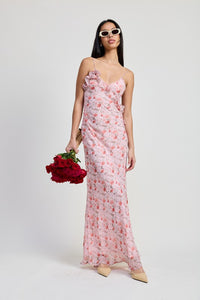 Woman wearing a floral dress holding red flowers against a white background