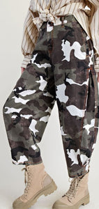Camouflage pants with a white ghost pattern worn with beige boots on a light background